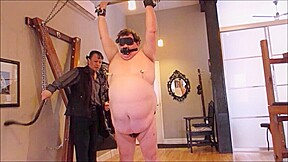 A Chub is chained to ceiling spanked forced to suck cock and fucked in Stocks